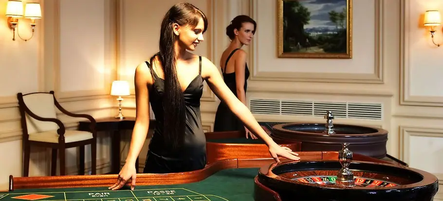 Two croupiers in black dresses at a roulette table in a panelled room, the promotional image used for LPE88 live dealer games